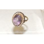 An unmarked gold, Victorian ring, set with central faceted oval amethyst, with a surround of split