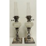 A pair of good quality Edwardian silver plate and cut glass oil lamps, each having squat circular