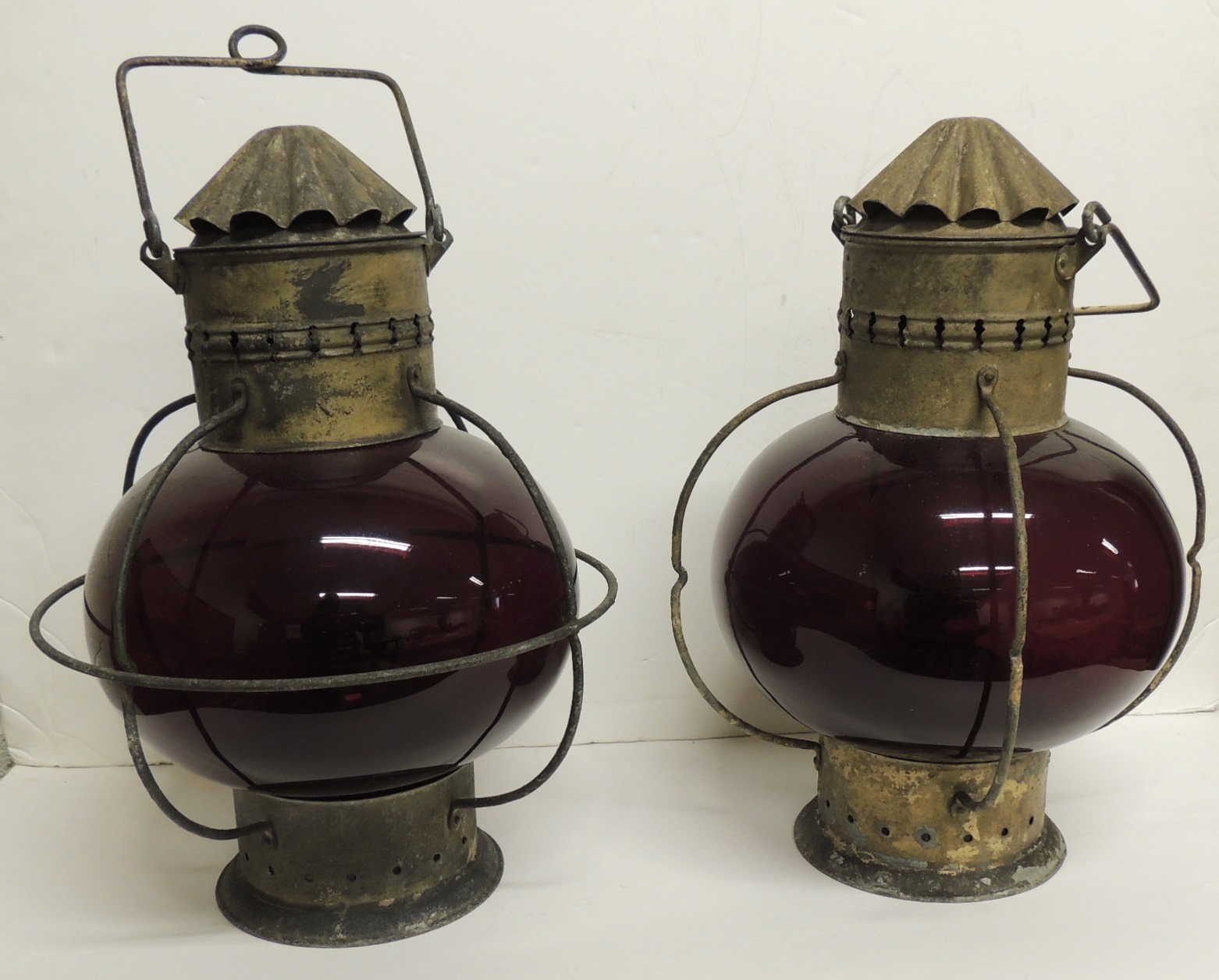 A pair of large red glass hanging lights with original burners, metal "chimneys" and swing handle,