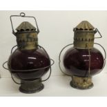 A pair of large red glass hanging lights with original burners, metal "chimneys" and swing handle,