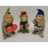 Three clockwork toy monkey musicians, each wearing a felt hat and with moulded felt face with