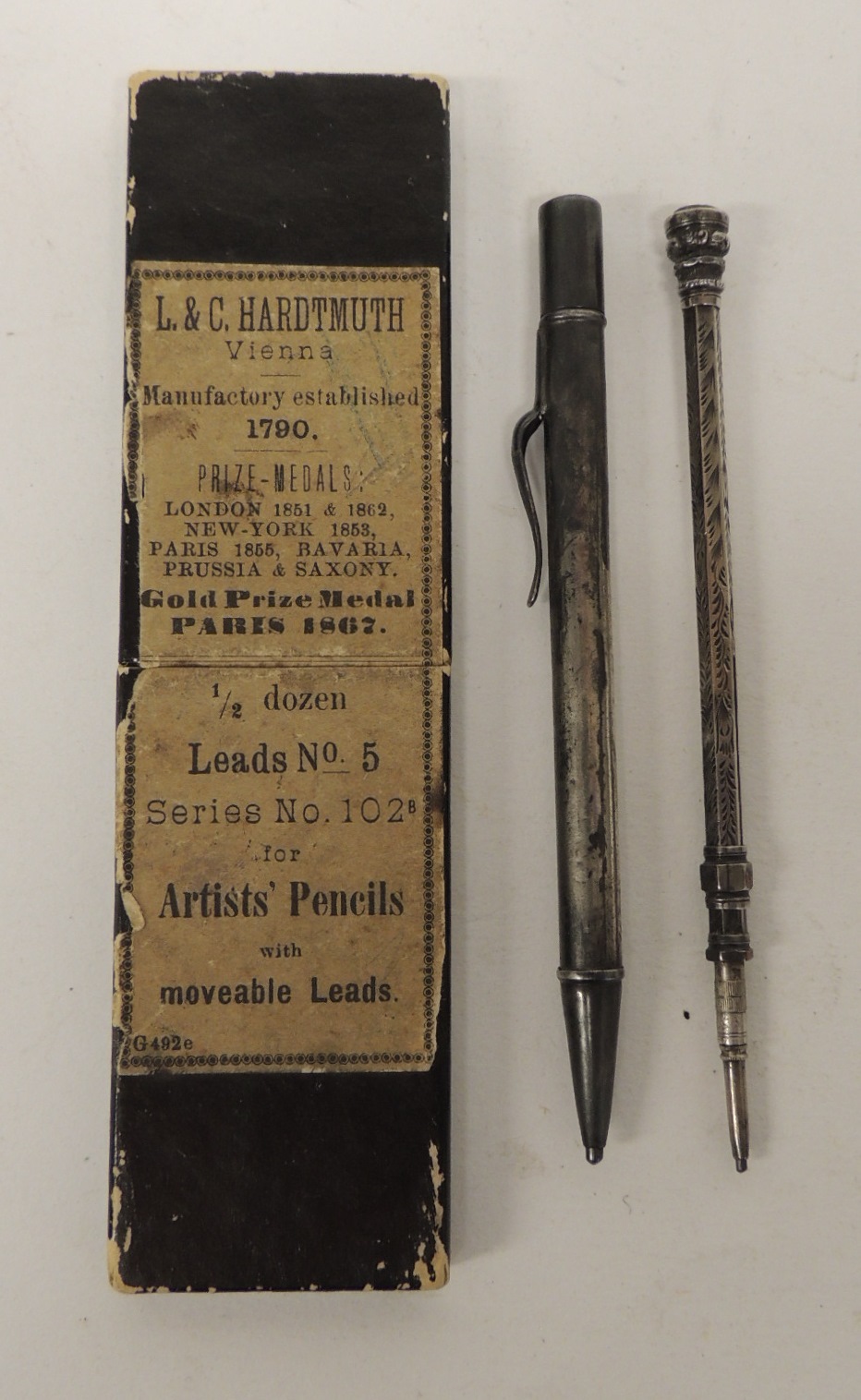 A silver cased propelling pencil together with an earlier silver metal cased pencil with slider