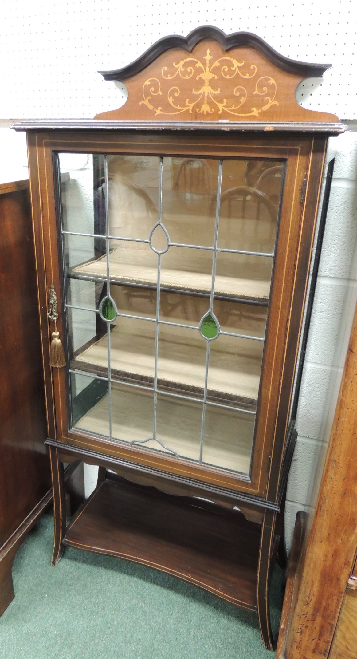 An early 20th century display cabinet, having inlaid raised back, leaded glass door enclosing two