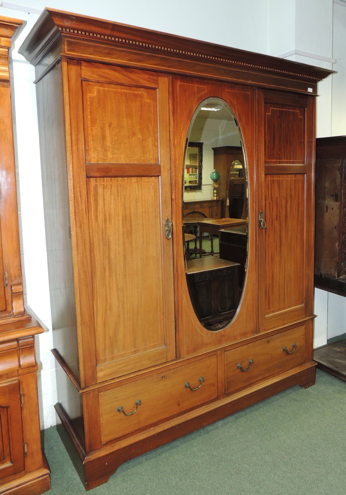 An early 20th century inlaid mahogany double wardrobe with moulded cornice, central oval bevelled