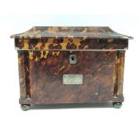 An early Victorian tortoiseshell tea caddy of sarcophagus form, the lid inlaid with mother of pearl,