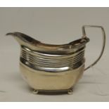 A George III silver cream jug of shaped rectangular form with gadroon edge, ribbed body and on