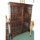 An early 20th century mahogany bookcase with dentil cornice, astragal glazed doors, enclosing
