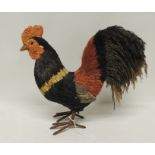 A decorative cockerel ornament, constructed from coloured grasses and with brown painted feet, 31cms