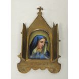 An early 20th Century porcelain plaque icon painted with the Virgin Mary within brass case having