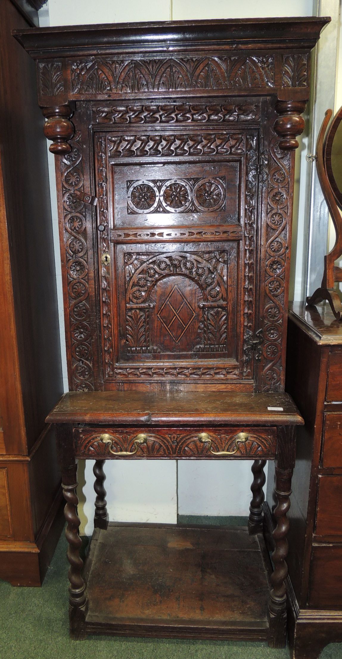A carved oak side cabinet comprising early carved cupboard, now fitted on an early carved oak