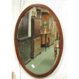 An oval inlaid mahogany wall mirror with bevelled glass plate.