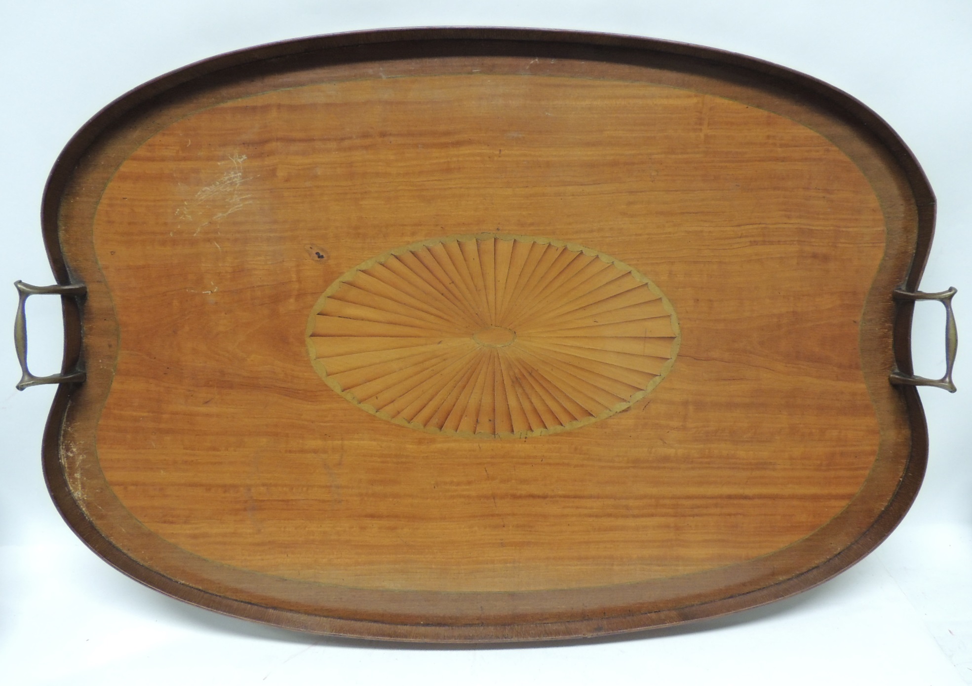 An early 20th Century shaped rectangular mahogany tray with brass handles and with central inlaid