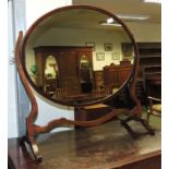 An early 20th century mahogany oval swing dressing mirror on shaped frame supports, 73cm high,