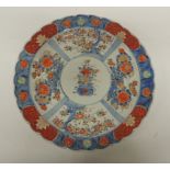 A Japanese Arita Imari charger painted in traditional palette with panels of prunus blossom and