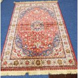 RED GROUND KASHMIR RUG WITH A FLORAL MEDALLION DESIGN 230 X 155CM