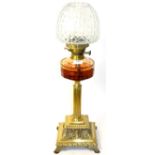 A Victorian brass column oil lamp with amber glass reservoir and clear glass shade