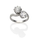 A Diamond Two Stone Twist Ring, two old cut diamonds in white claw settings, to twist shoulders pavé