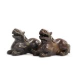 A Pair of Chinese Carved Hardwood Figures of Lion Dogs, Qing Dynasty, recumbent with scrolling manes