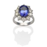 An 18 Carat White Gold Tanzanite and Diamond Cluster Ring, an oval cut tanzanite within a border