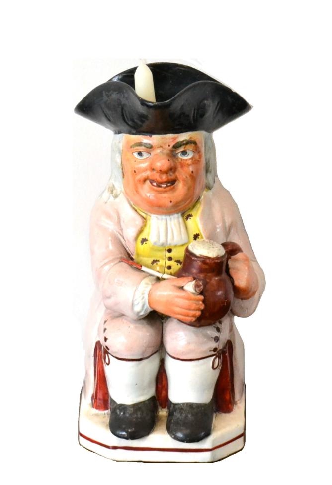 A Staffordshire Pearlware Ruddy-Faced Toby Jug, early 19th century, wearing a black hat and lilac