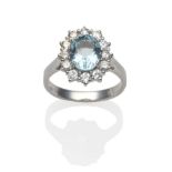 An 18 Carat White Gold Aquamarine and Diamond Cluster Ring, an oval cut aquamarine within a border