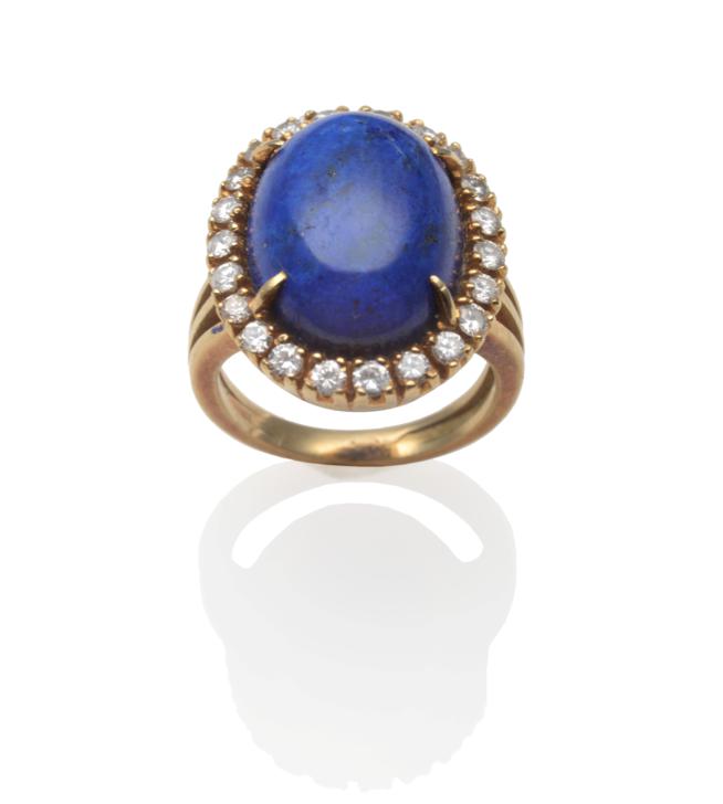 A Lapis Lazuli and Diamond Cluster Ring, an oval cabochon lapis lazuli within a border of round