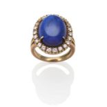 A Lapis Lazuli and Diamond Cluster Ring, an oval cabochon lapis lazuli within a border of round