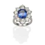 A Sapphire and Diamond Cluster Ring, an oval cut sapphire within a border of old cut diamonds in