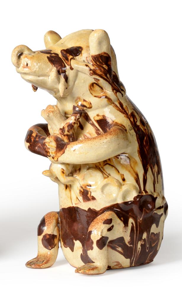 A Slipware Model of a Seated Bear, 19th century, modelled seated holding a dog in its front paws,