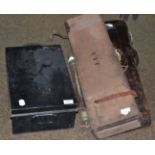 A canvas-covered shotgun case; a leather leg-o'-mutton gun case; a japanned tin box and a military