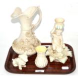 Four pieces of Belleek porcelain including a jug, chamberstick, vase and dog