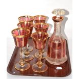 A set of gilt highlighted cranberry glass wines together with a matching decanter