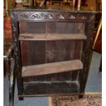 A late Victorian carved oak bookcase, with lunette carved frieze above carved stiles with adjustable