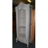 A cream painted grille door cabinet in the Louis XV style, with a carved pediment above an arched