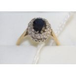 A sapphire and diamond cluster ring, an oval cut sapphire within a border of eight-cut diamonds in