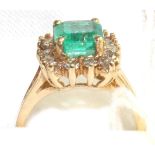 An emerald and diamond cluster ring, an emerald-cut emerald within a border of round brilliant cut