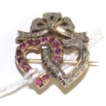 A ruby and diamond twin heart brooch, one heart set with round cut rubies in yellow claw settings,