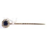 A sapphire and diamond stick pin, a round cut sapphire within a border of old cut diamonds in yellow