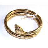 A 9 carat gold snake bangle, with faceted ruby eyes and foliate engraved head to a coiled