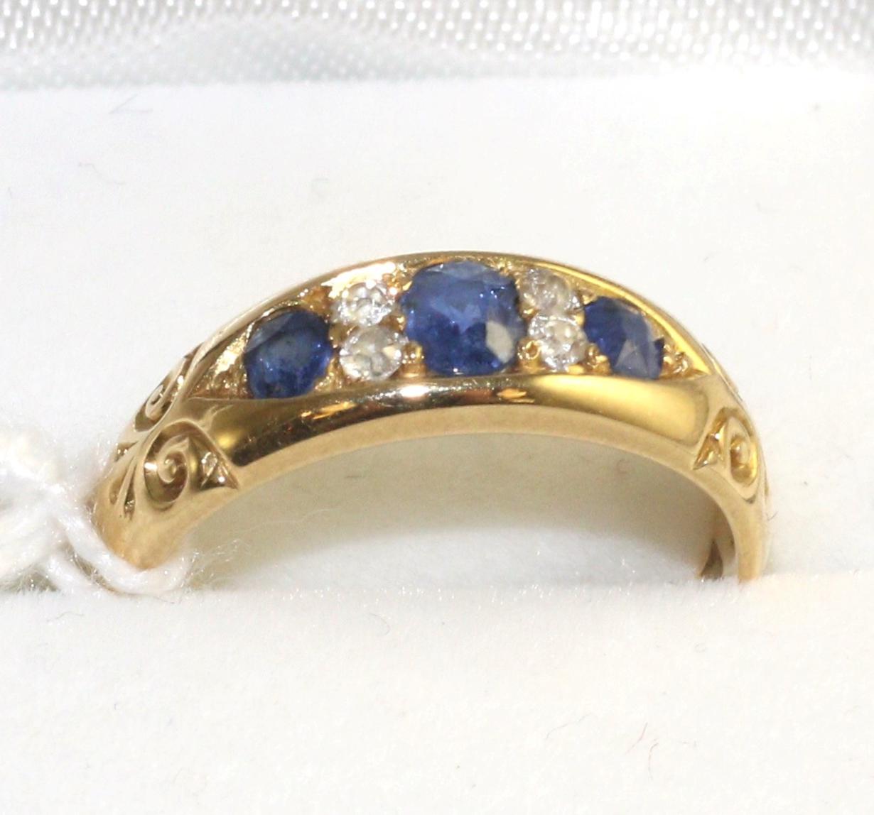 An 18 carat gold sapphire and diamond cluster ring, three oval cut sapphires spaced by old cut