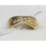 An 18 carat gold diamond half hoop crossover ring, channel set with round brilliant cut diamonds, on