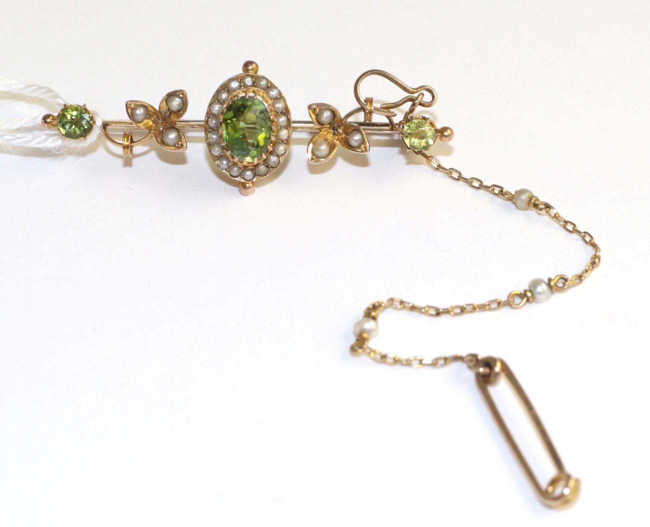 A peridot and seed pearl bar brooch, an oval cut peridot in a yellow claw setting within a border of