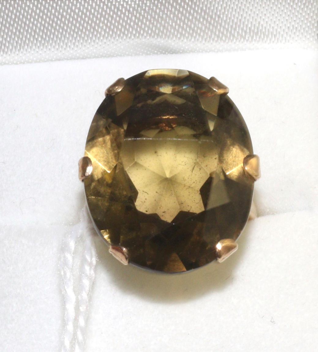 A smokey quartz ring, an oval cut smokey quartz in a yellow claw setting with pierced underbezel, on