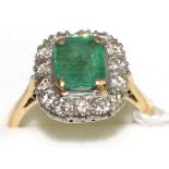 An emerald and diamond cluster ring, an emerald-cut emerald in a yellow claw setting, within a