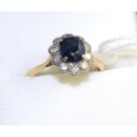 A sapphire and diamond cluster ring, an oval cut sapphire within a border of round brilliant cut