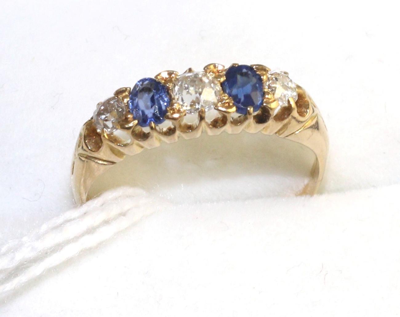 An 18 carat gold sapphire and diamond ring, three old cut diamonds spaced by two oval cut