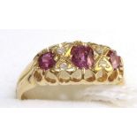 An 18 carat gold ruby and diamond ring, three graduated oval cut rubies spaced by rose cut diamond