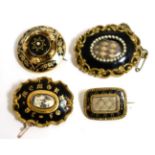 A group of four Victorian enamel and yellow metal mounted mourning brooches