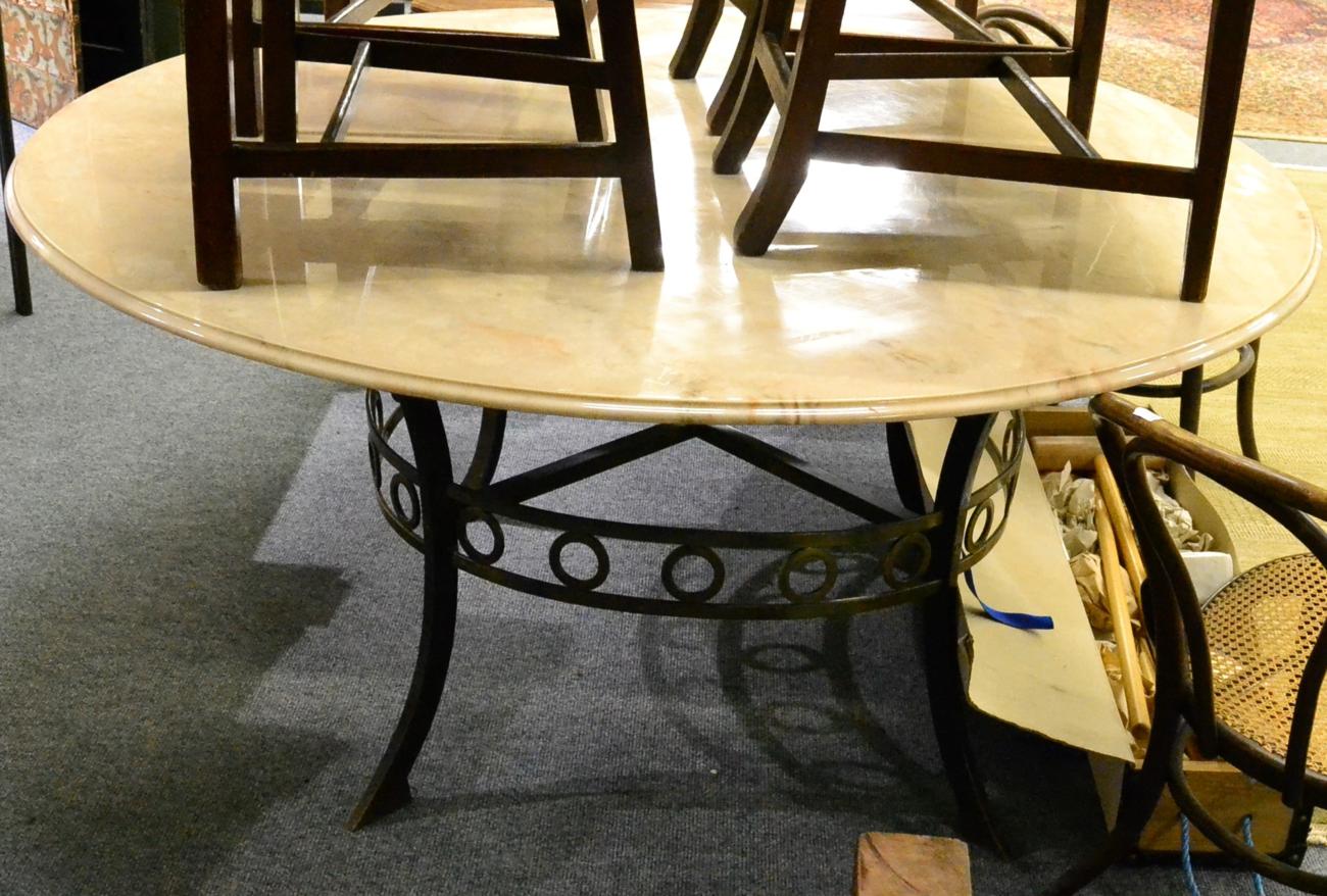 A circular pink composition marble dining or centre table, raised on a wrought iron base with