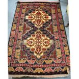 An Afghan Balouch rug, the field with twin ivory medallions enclosed by triple borders, 178cm by
